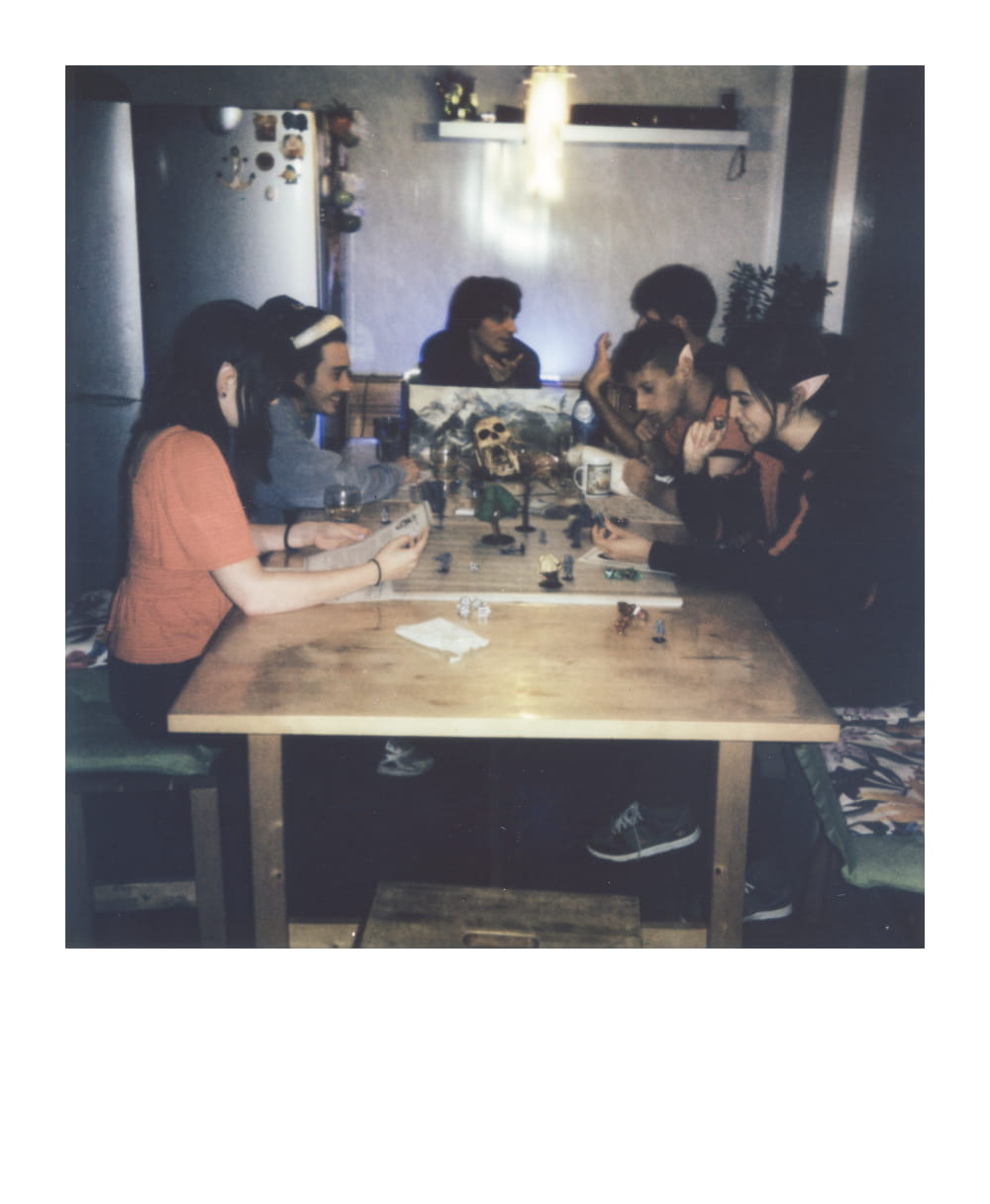 Grande grupo jogando Dungeons & Dragons em casa com miniaturas e uma tela de mestre de masmorras